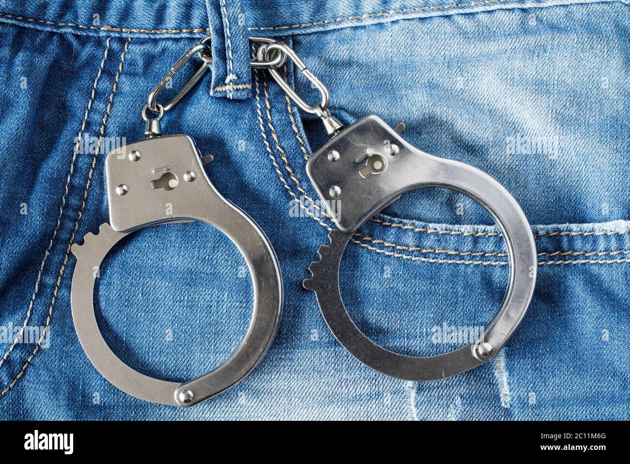 Handcuffs hanging on a belt of jeans Stock Photo