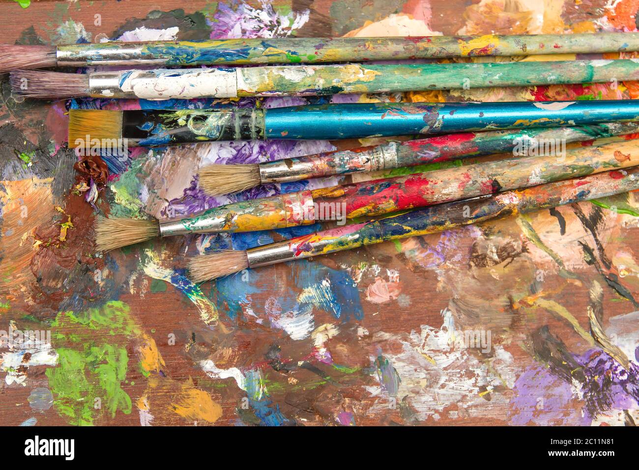 Old paintbrushes on splattered artist table Stock Photo