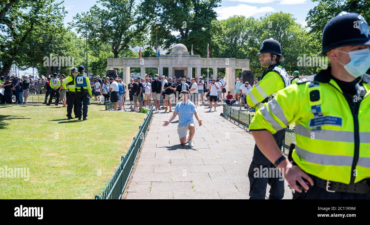Brighton UK 13th June 2020 - One of the men believed to be part of right wing groups goes down on his knee at the war memorial as  at the war memorial thousands take part in the Black Lives Matter anti racism protest rally through Brighton today . There have been protests throughout America , Britain and other countries since the death of George Floyd while being arrested by police in Minneapolis on May 25th : Credit Simon Dack / Alamy Live News Stock Photo