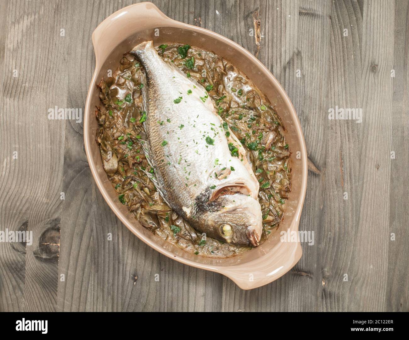 Fish cooked bream baked with stewed artichokes Stock Photo