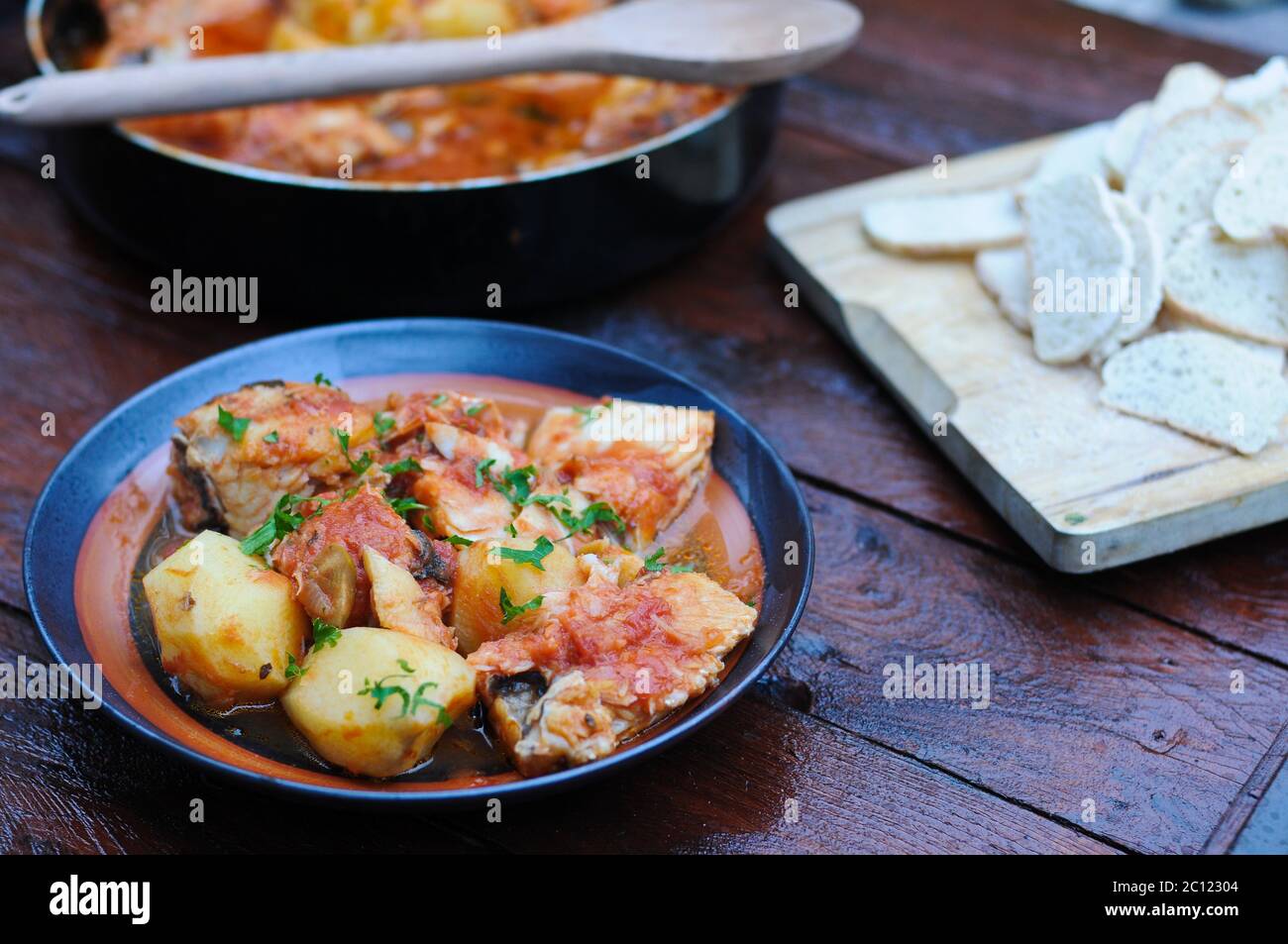 cod cooked in a pan with tomato, olives and potatoes Stock Photo