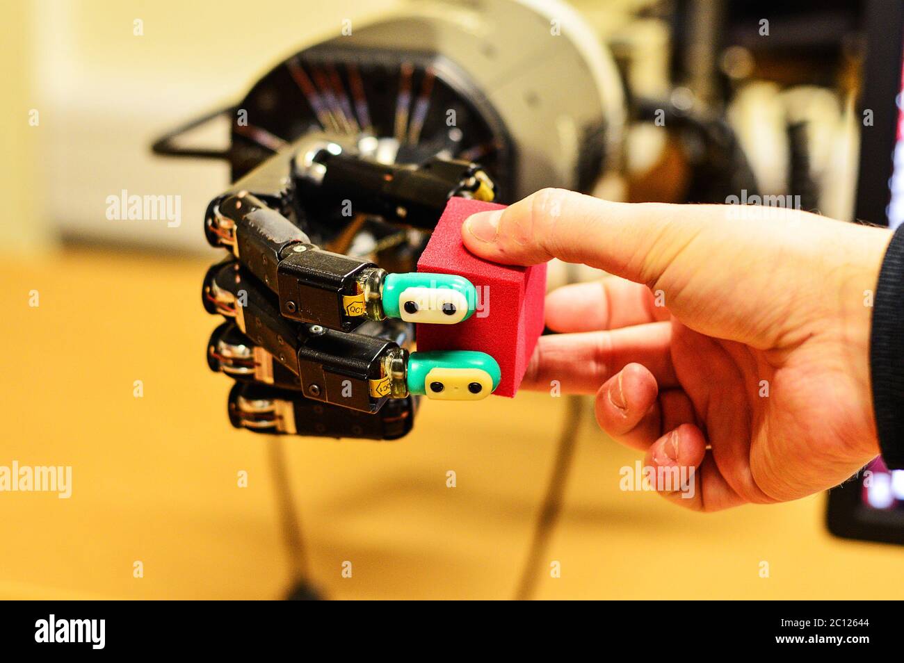 Man and Robot Hand Holding a Red Cube in Research Laboratory Stock Photo