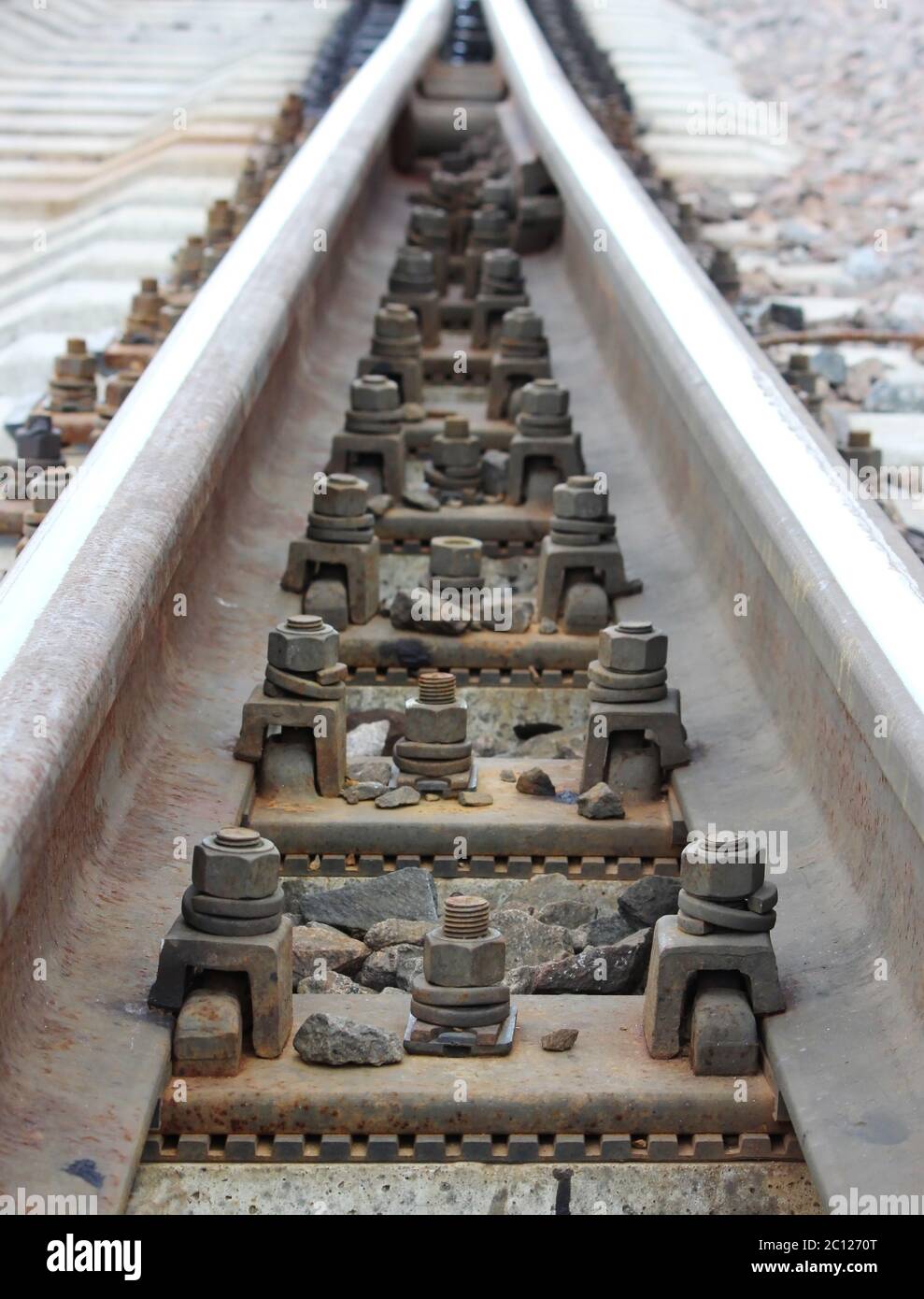 bolts that secure the rails to the sleepers on the railway direction. Stock Photo