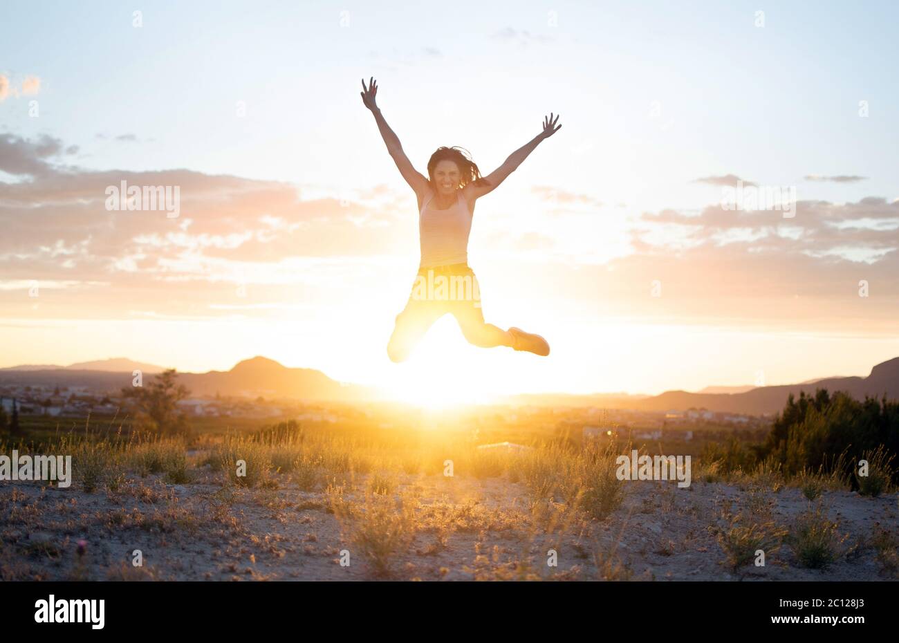 https://c8.alamy.com/comp/2C128J3/athletic-young-girl-jumping-freely-at-mountain-top-against-sunset-in-murcia-spain-doing-exercise-work-out-training-attractive-fit-healthy-woman-in-2C128J3.jpg