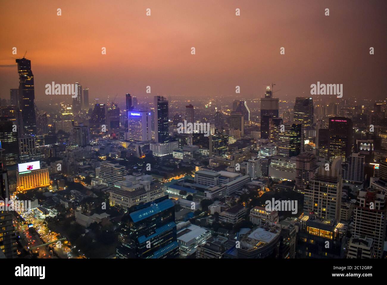The enlightened skyscrapers of Bangkok skyline during orange sunset in Thailand Stock Photo