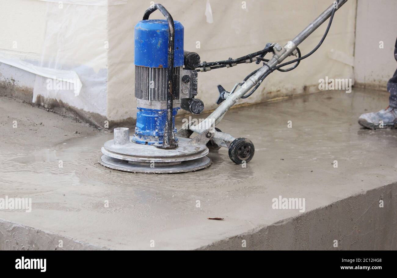 male worker works with the diamond grinding machine, polishing the porch in front of the office