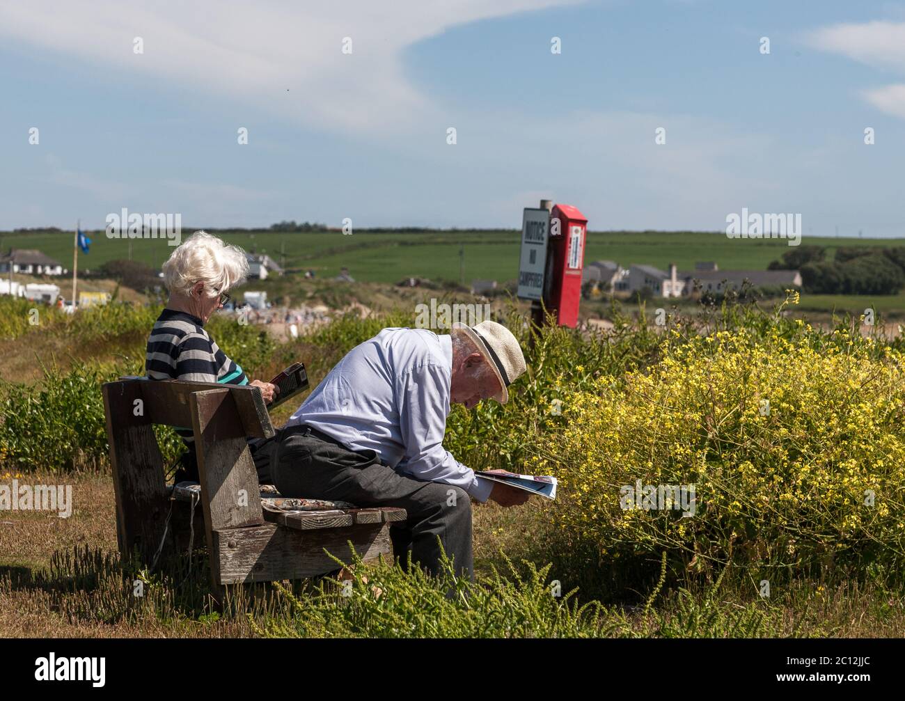 Garrylucas, Cork, Ireland. 13th June, 2020. On the first weekend since the Covid-19 lockdown restrictions were lifted an elderly couple sit and read on a bench at Garrylucas Beach, Co. Cork, Ireland.  - Credit; David Creedon / Alamy Live News Stock Photo