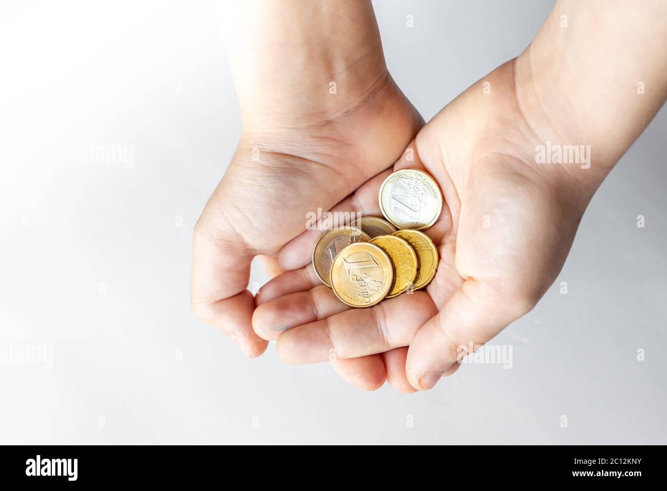 Closeup child's hands holding Euro coins isolated on white background ...
