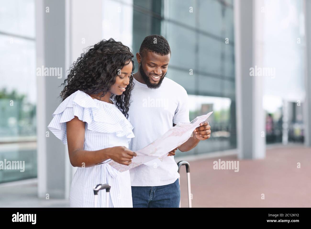 Honeymooners couple looking at city map after arriving to new airport Stock Photo
