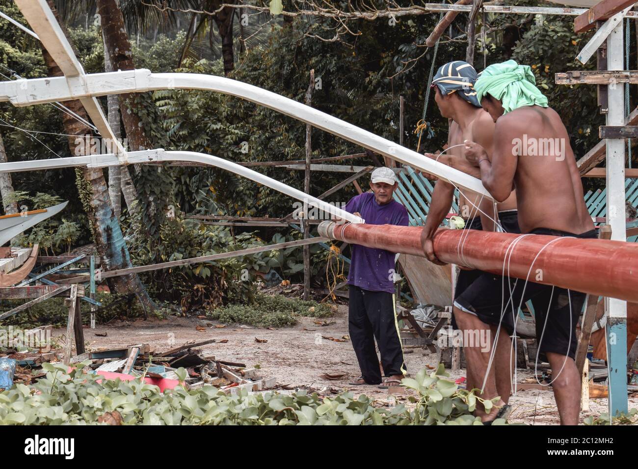 Philippine tribal fisherman repairing the float of a traditional fisherman boat on a beach in Port Barton in the Philippines Palawan Island Stock Photo