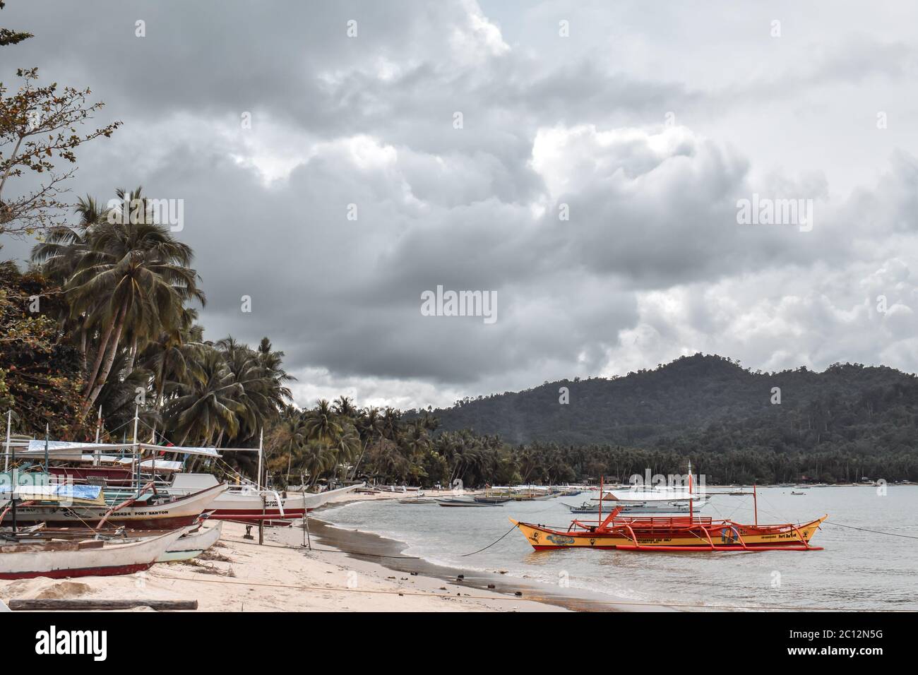 Traditional Philippine fisherman boats docked on a beach in a lagoon in Port Barton Palawan Island the Philippines before a storm Stock Photo