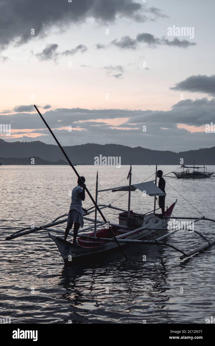 Two traditional Philippino fishermen on the horizon returning home on ...