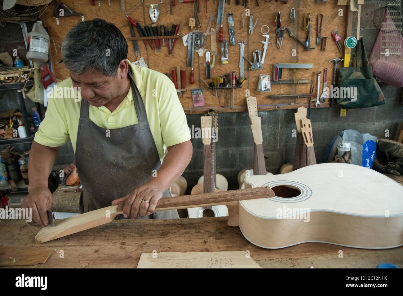 Luthier Panfilo Enriquez works on a custom guitar in his workshop in Paracho, Michoacan, Mexico. Stock Photo