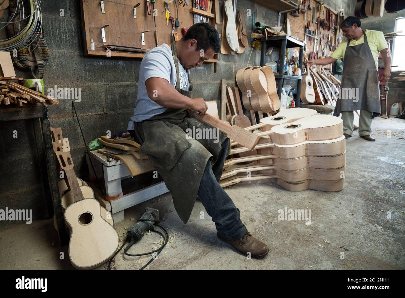 Luthiers Claudio and Panfilo Enriquez work on a custom guitars in their workshop in Paracho, Michoacan, Mexico. Stock Photo