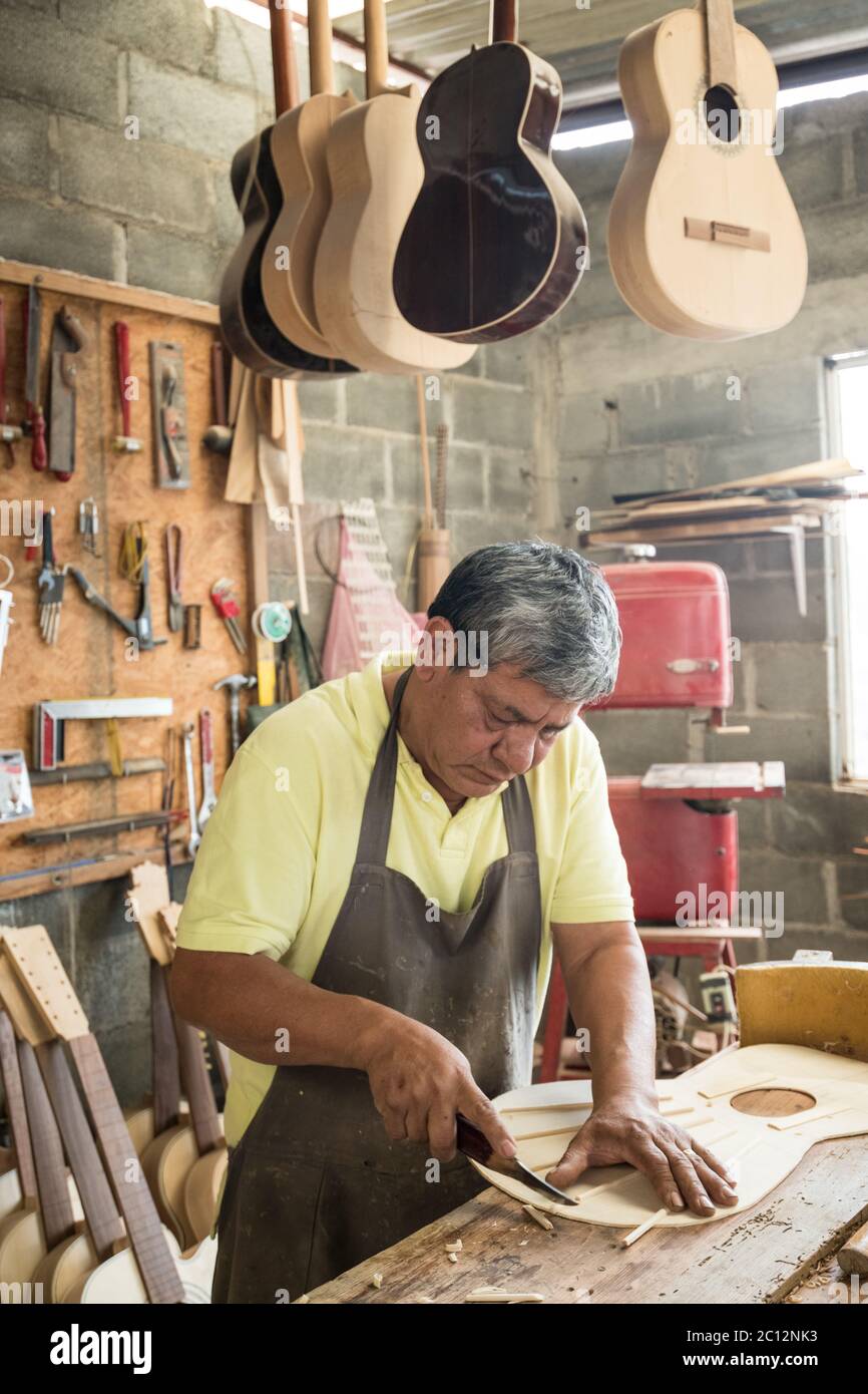 Luthier Panfilo Enriquez works on a custom guitar in his workshop in Paracho, Michoacan, Mexico. Stock Photo