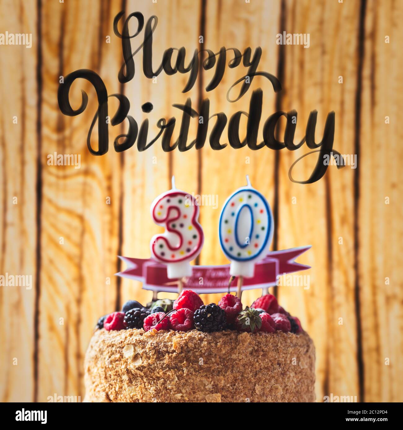 raspberries blackberry cake with candles number 30 on wood background and Happy Birthday lettering Stock Photo