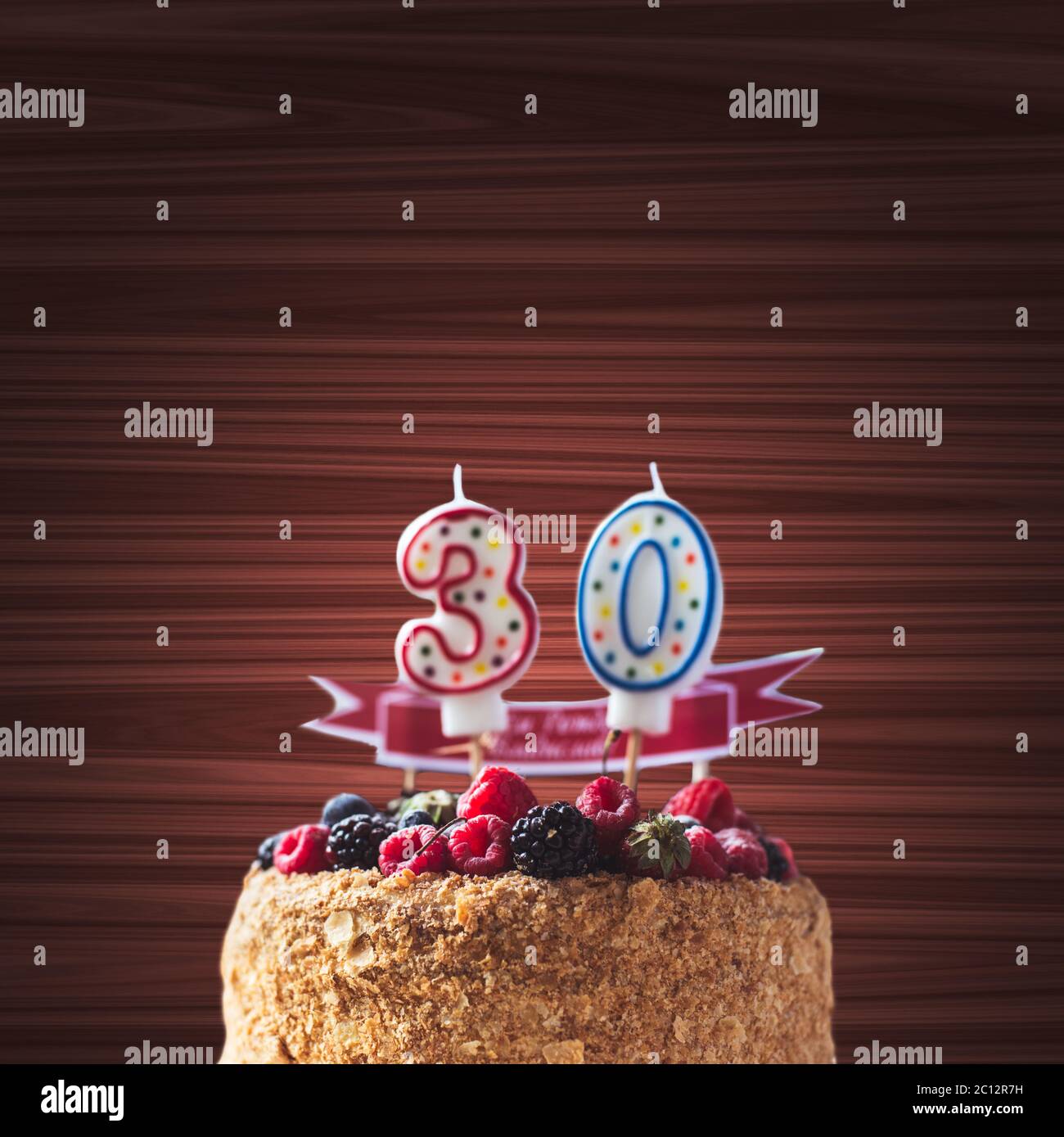 raspberries blackberry birthday cake with candles number 30 on wood background and copyspace for your text Stock Photo