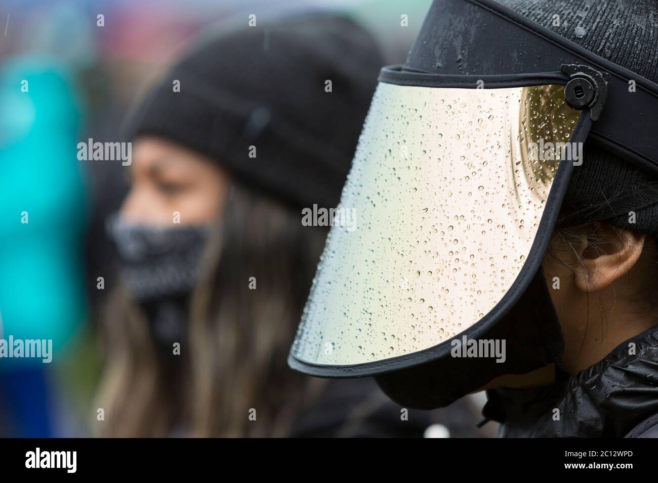 A supporter in a face shield braved heavy rains to attend the Statewide Silent March and General Strike at Judkins Park in Seattle's Central District neighborhood on Friday, June 12, 2020. Black Lives Matter Seattle-King County organized the statewide day of action and silent march to honor lives lost in support of all Black lives in Washington State. Stock Photo