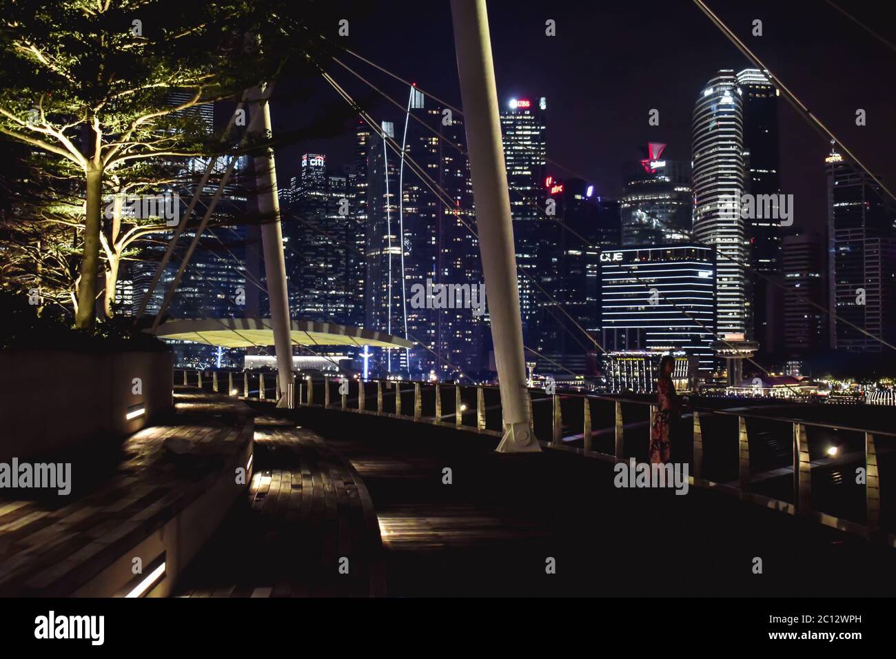 Girl observing the Singapore skyline in night from the rooftop of Marina Bay Link Mall Singapore Stock Photo