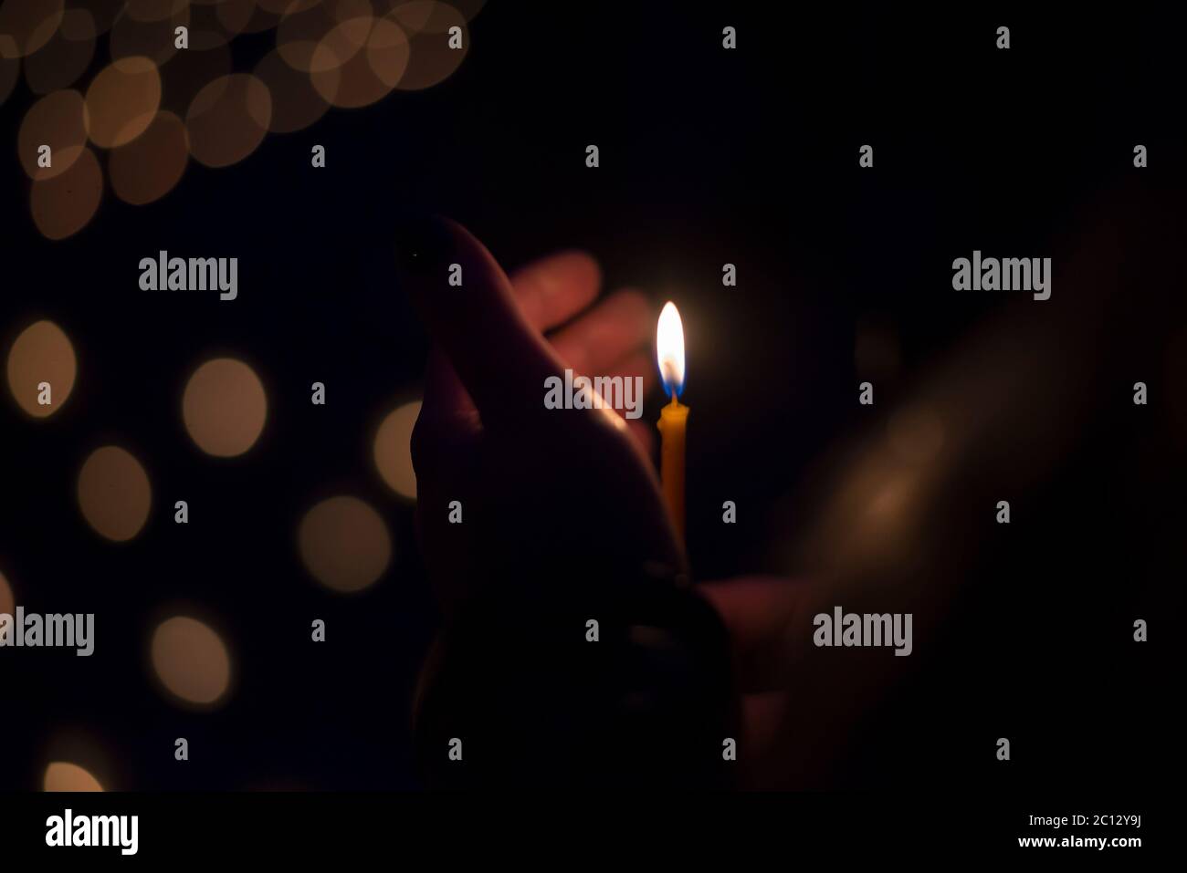 Hand holding a thin burning candle in the dark Stock Photo - Alamy