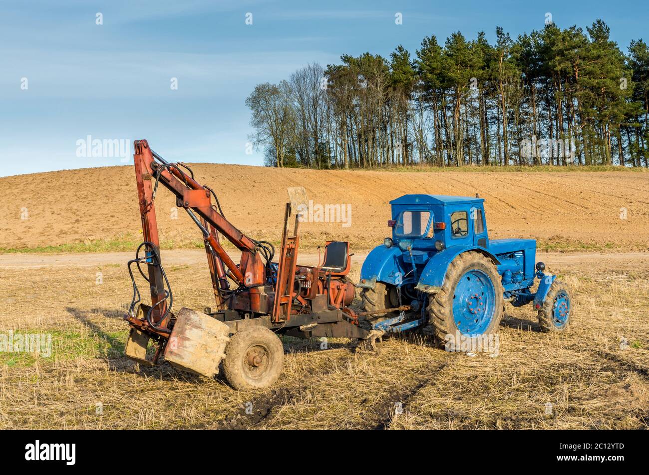 Old russian tractor with loader in Lithuanian fields Stock Photo