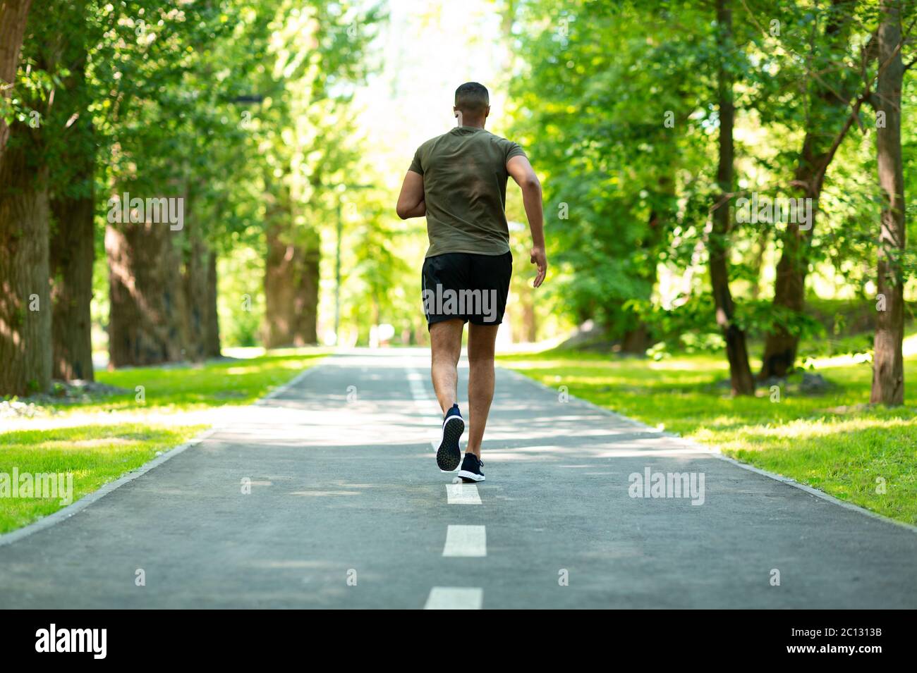 Back view of African American sportsman on jogging track at beautiful park Stock Photo