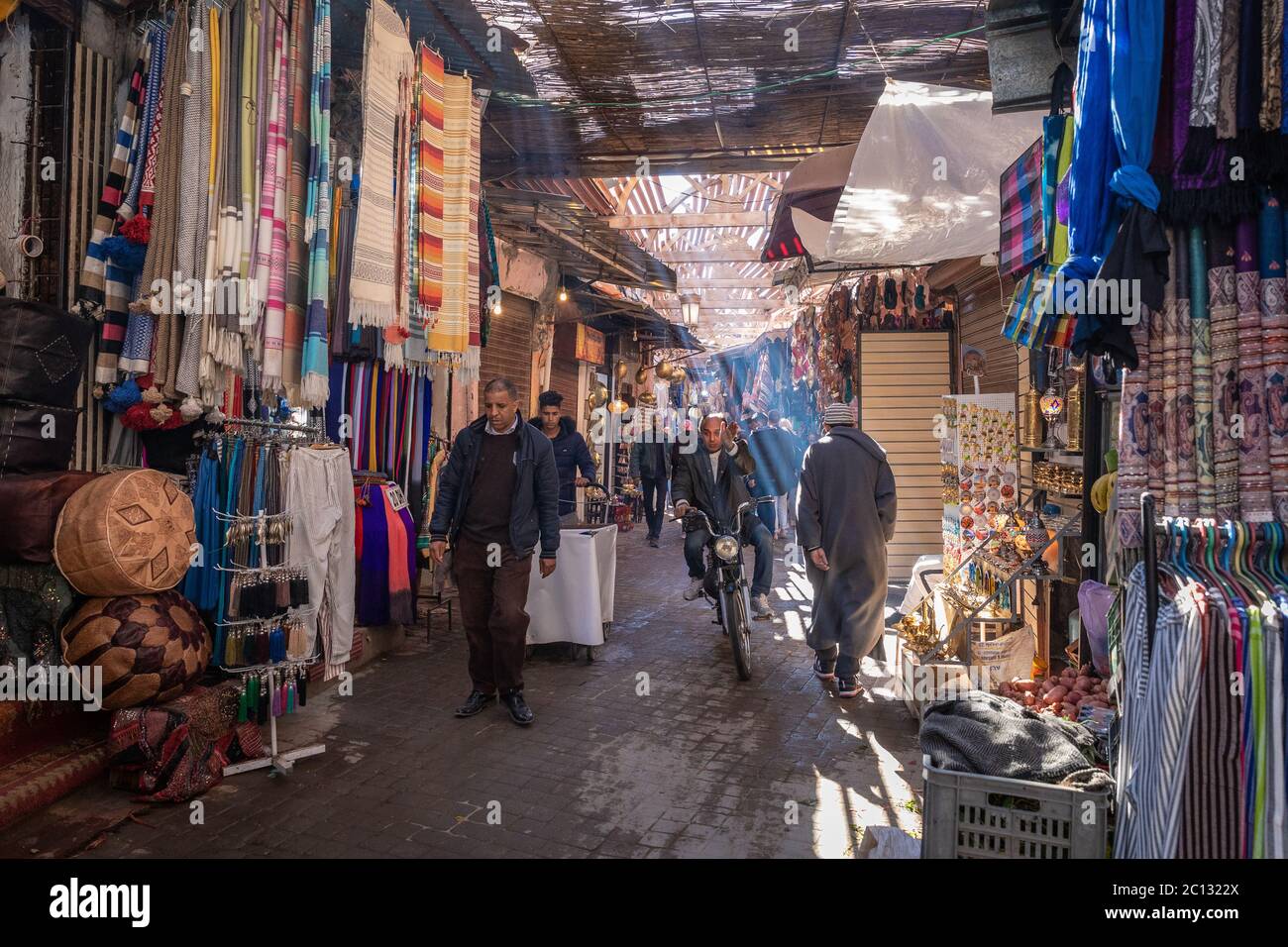 Souks, shoppers and tourists inside the medina with daylight streaming in in Marrakech, Morocco Stock Photo