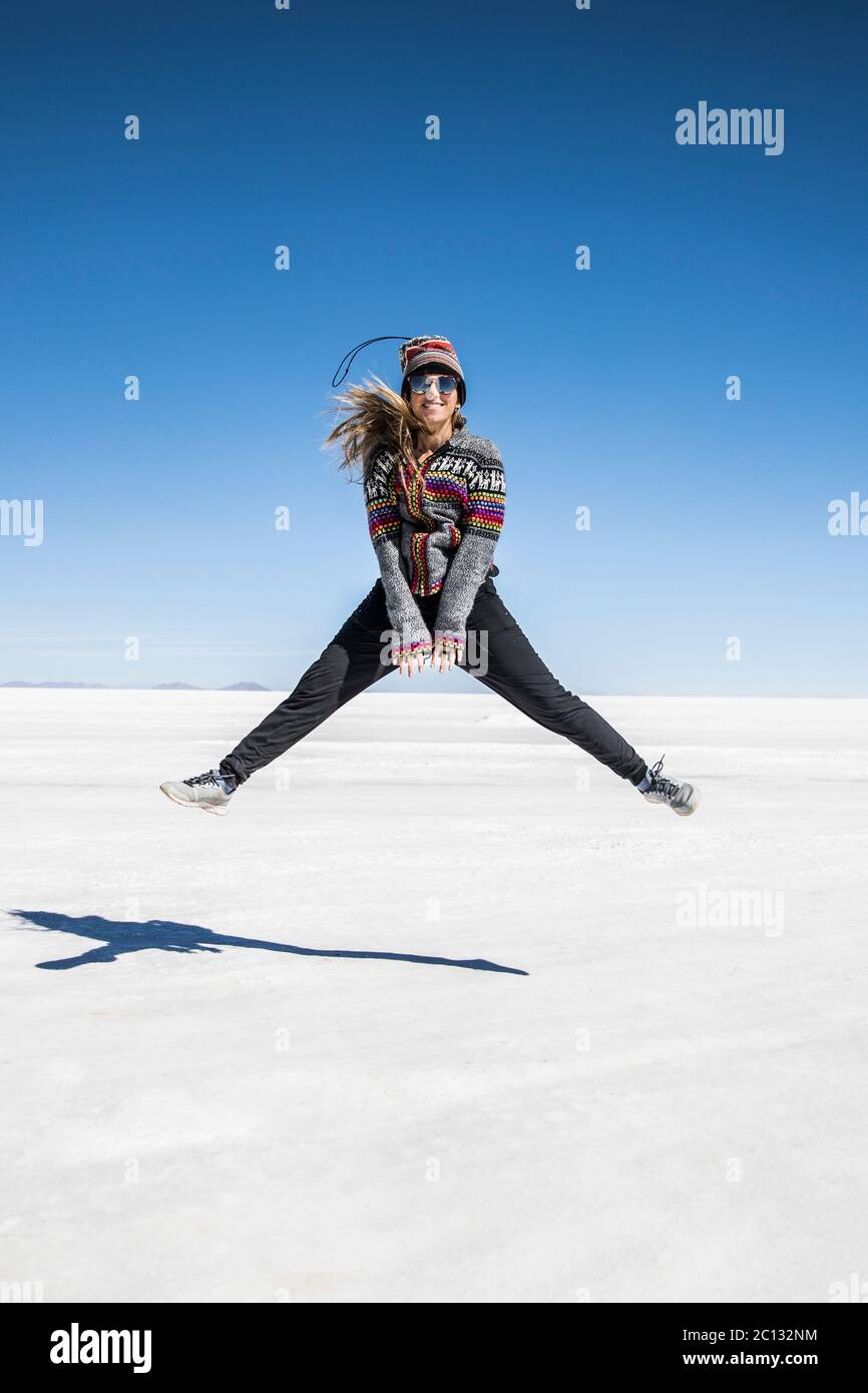 beautiful woman jumping in salt flats with blue sky in the background Stock Photo