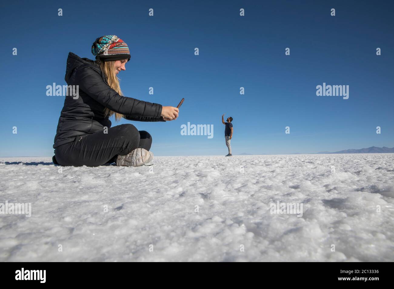 Couple playing in the desert salt flats, having fun with perspective Stock Photo