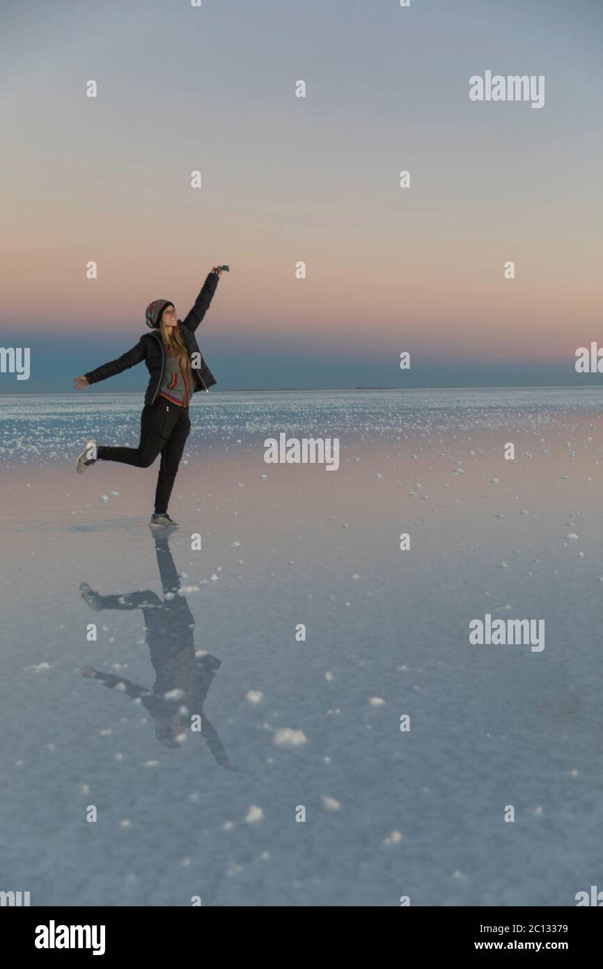 beautiful caucasian woman in salt flats with gorgeous reflections posing in sunset Stock Photo