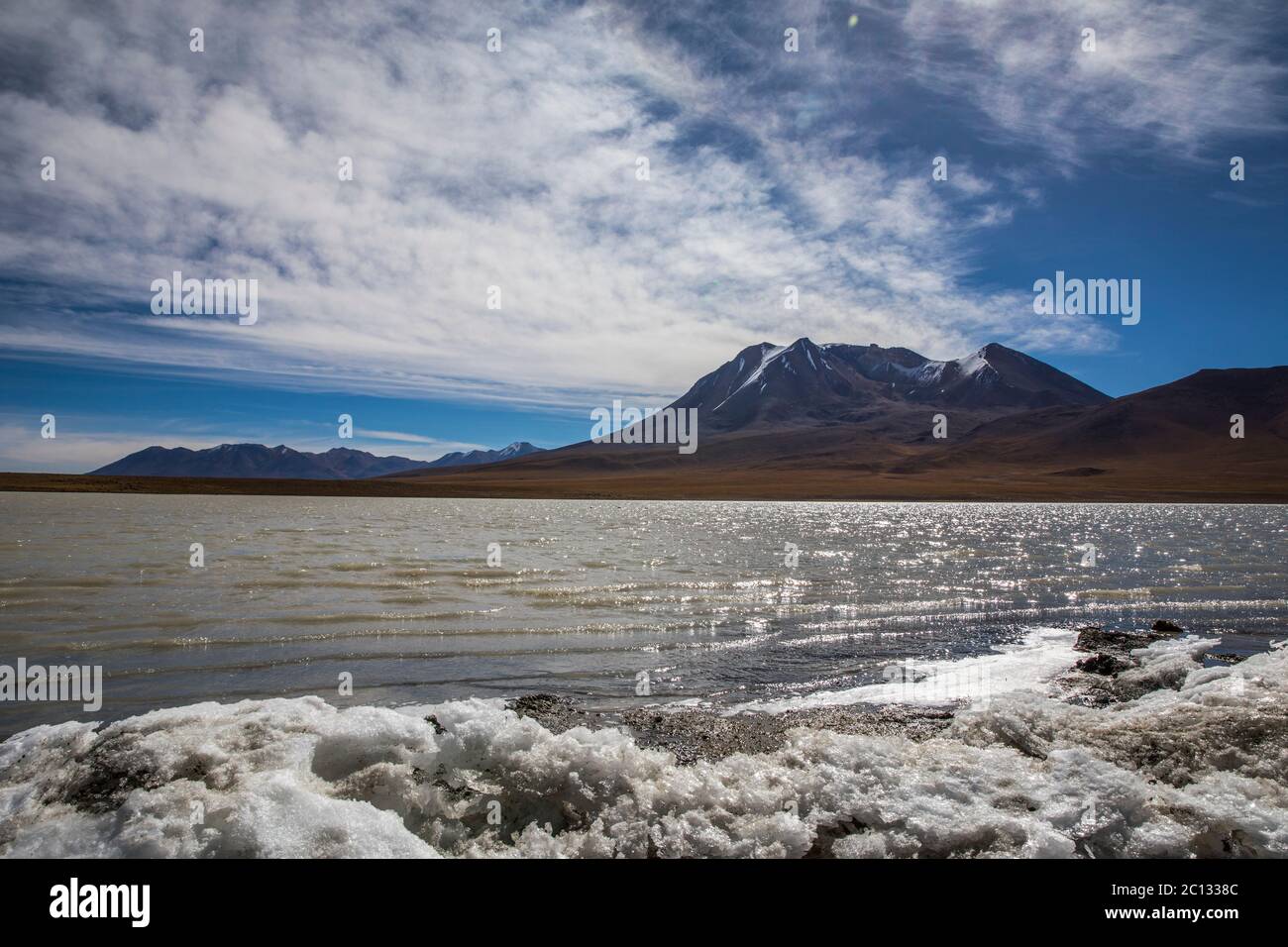 lake defrosting in the desert of bolivia with a volcano on the background Stock Photo