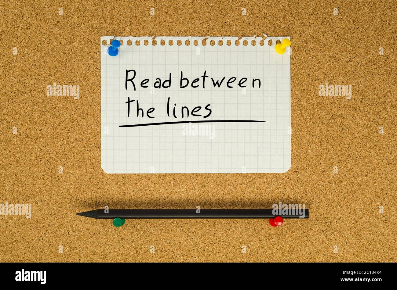 Read between the lines text note message pin on bulletin board Stock Photo