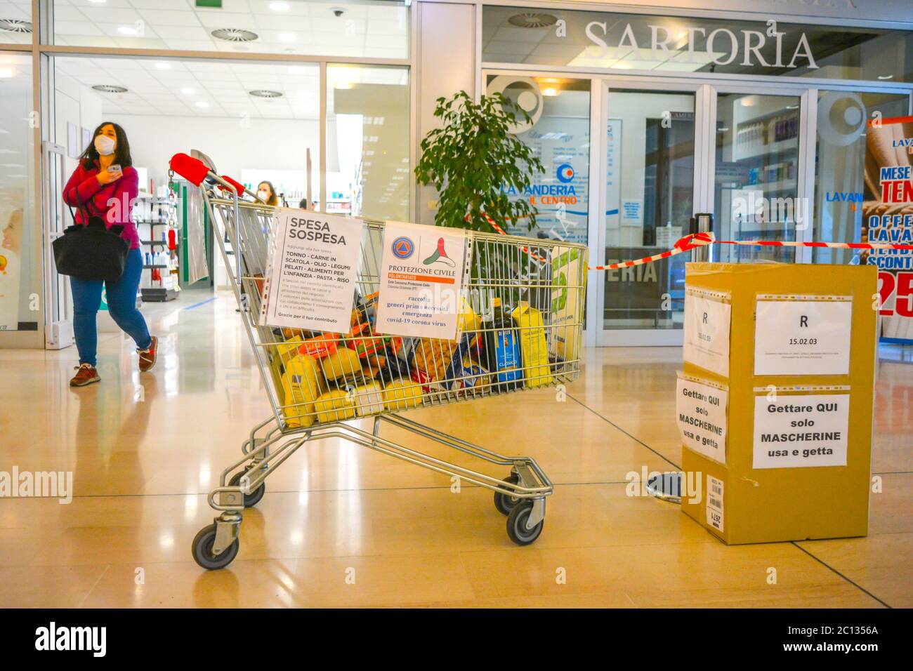 Solidarity inside an italian grocery store: a shopping cart full of donated food for poor people. Suspended shopping (spesa sospesa) charity for covid Stock Photo