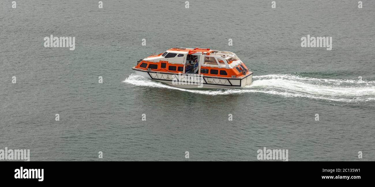 Orange-and-white life boat moving fast in the water. Life saving equipment concept. Stock Photo
