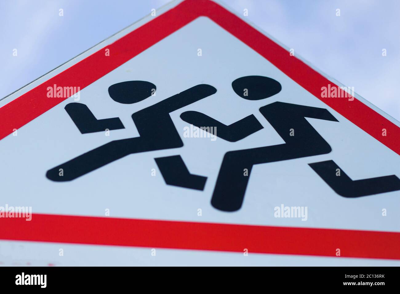 Information road sign, triangular white shield with running figures. Attention, school ahead, reduce speed recommendation. Stock Photo