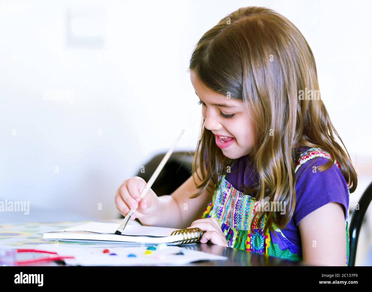 Portrait of a cute smiling girl painting a picture Stock Photo - Alamy