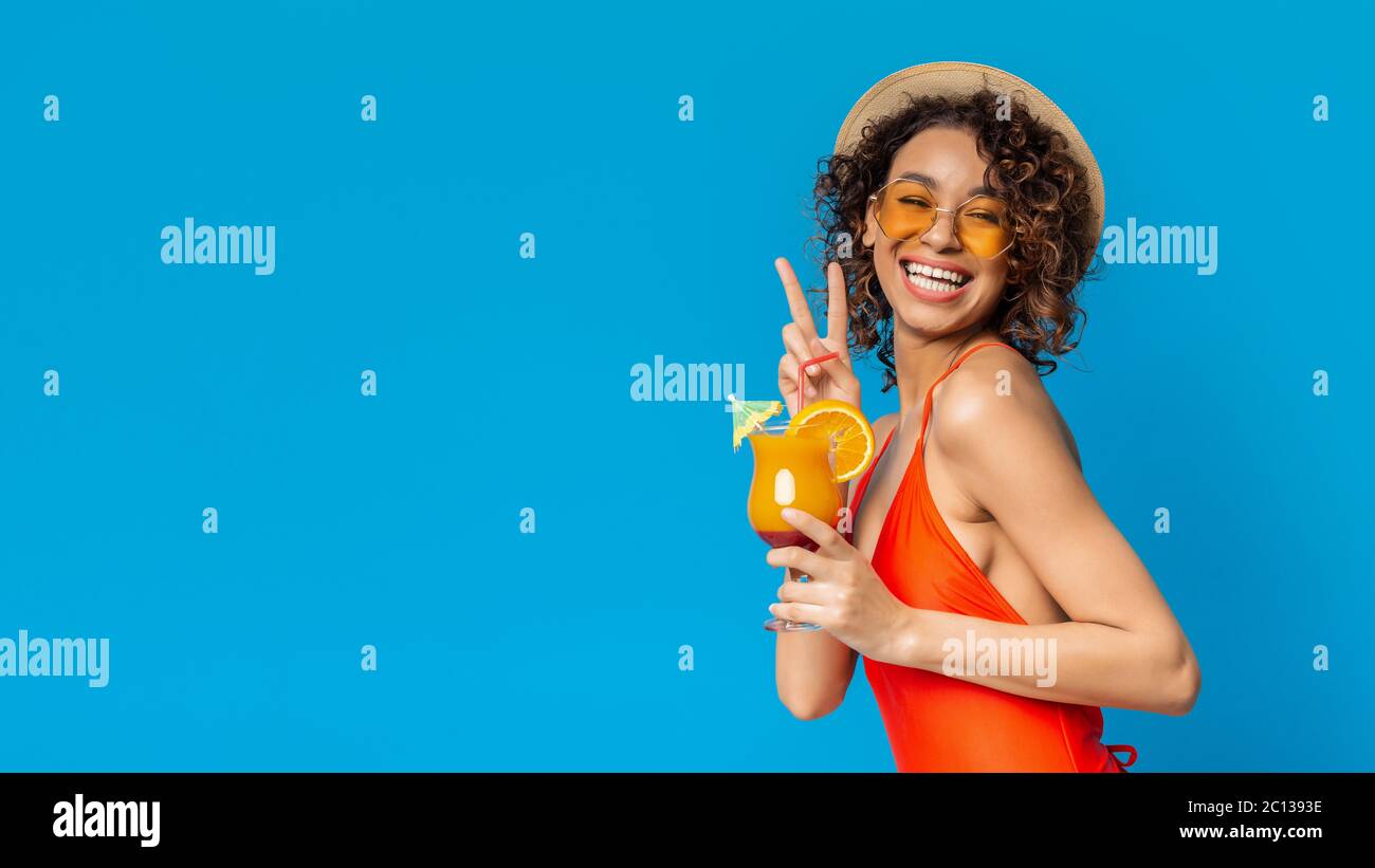 Summer afro girl in swimsuit drinking fruit cocktail and showing peace gesture Stock Photo