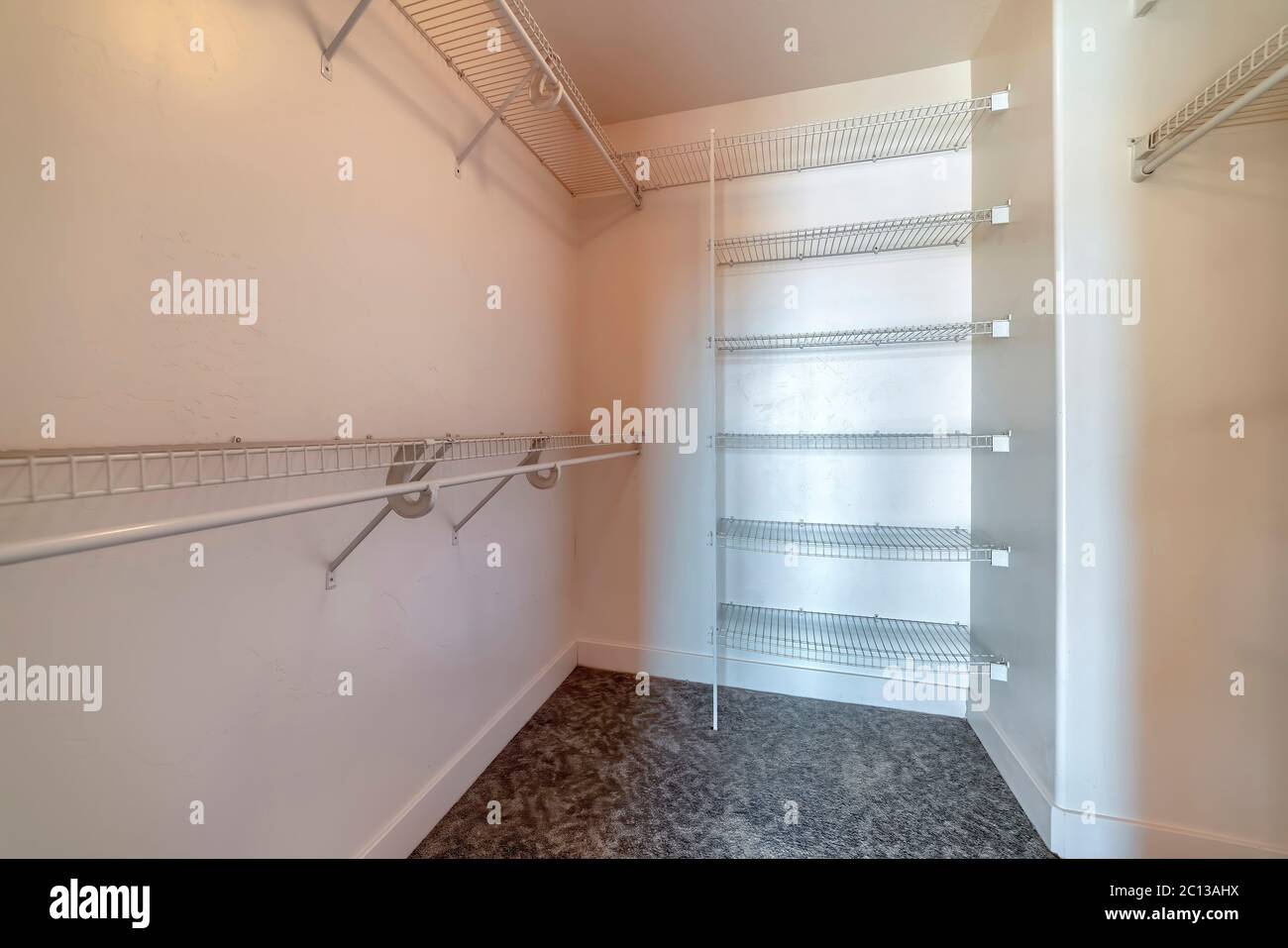 Walk in closet with metal racks and hanging rods mounted on plain white wall Stock Photo Alamy