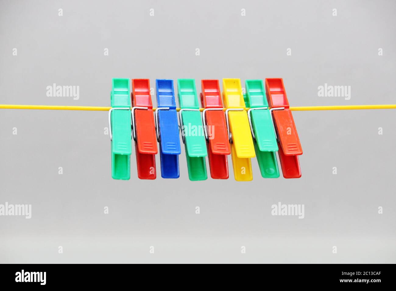 colored plastic clothespins hanging on the rope. Stock Photo