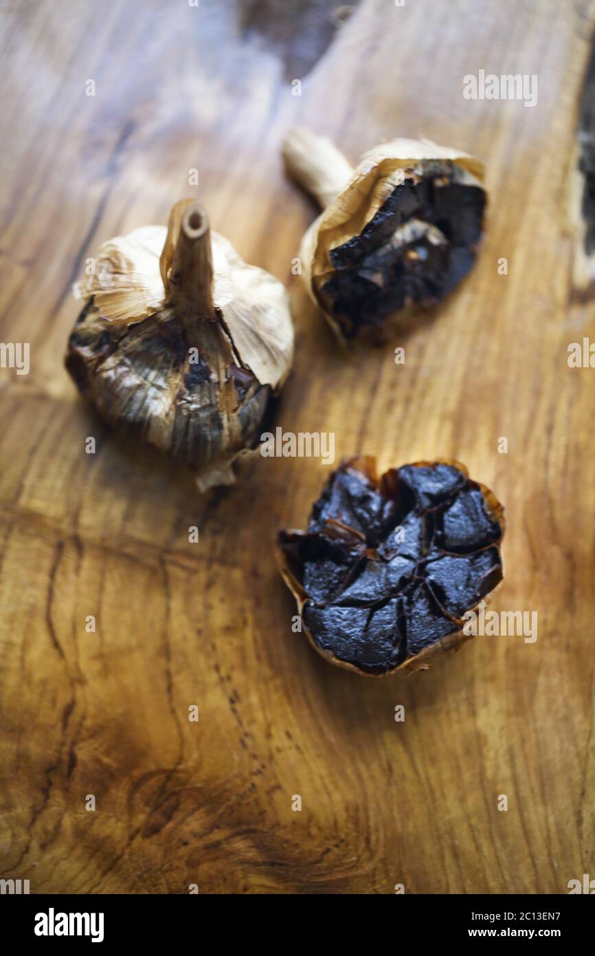 Black garlic bulbs and cloves on wooden background Stock Photo