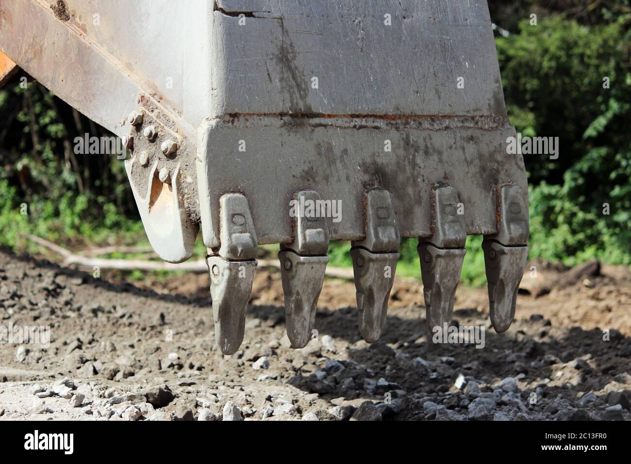 Excavator bucket digging a trench at the side of the road for its expansion Stock Photo Alamy