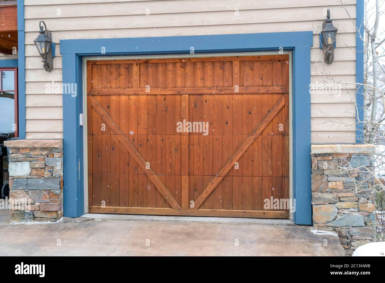 Brown wood garage door with blue frame flaned by wall mounted vintage