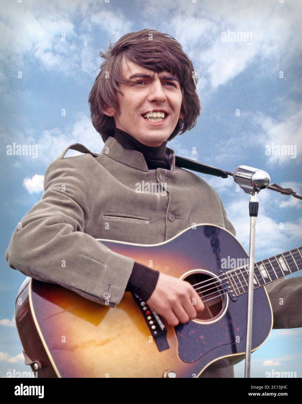 George Harrison performs “I Need You” on the movie set of HELP! Filmed on Salisbury Plain, Wiltshire. May 4, 1964. Stock Photo