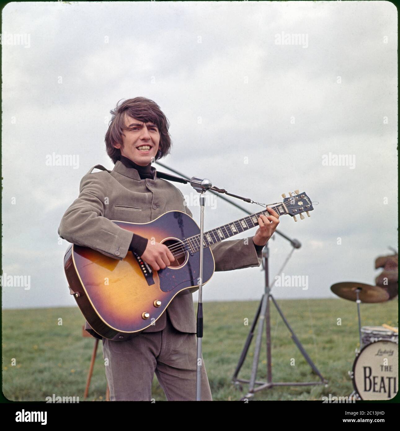 George Harrison performs “I Need You” on the movie set of HELP! Filmed on Salisbury Plain, Wiltshire. May 4, 1964. Image from 6x6 cm transparency. Stock Photo