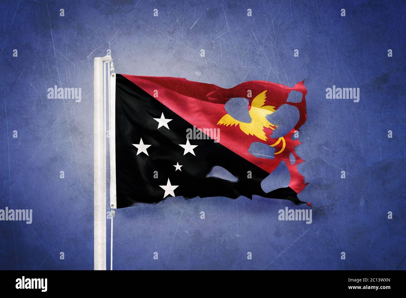 Torn flag of Papua New Guinea flying against grunge background Stock Photo