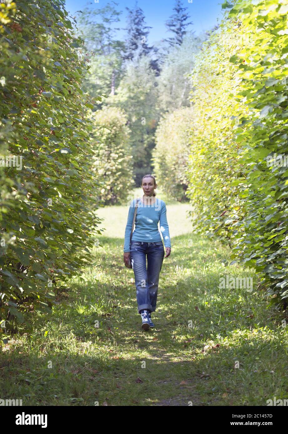 The young woman in a blue jacket walks in summer park. Stock Photo