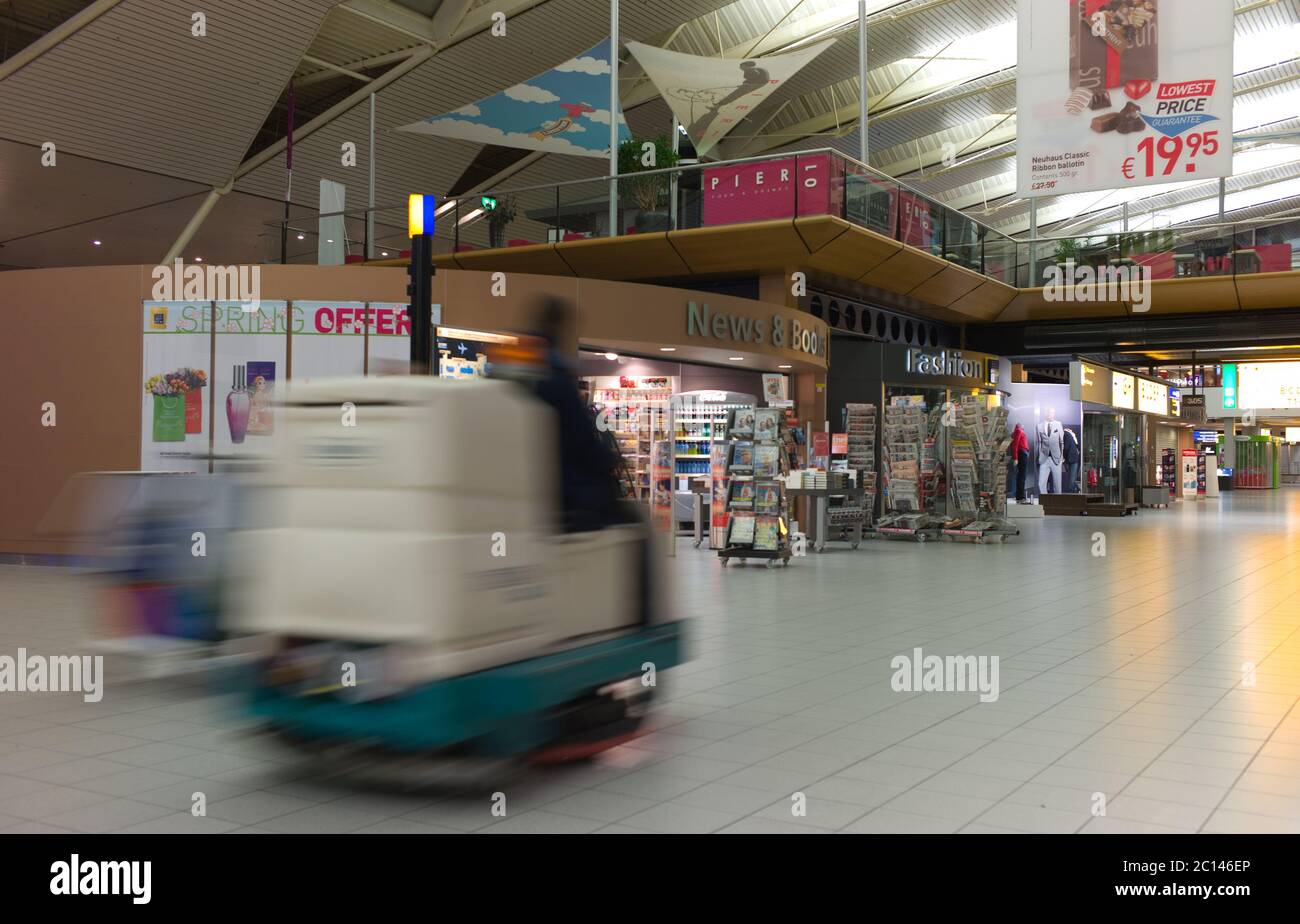 Machine for cleaning floors drives through the hall with shops and tourists in Schiphol International Airport in Amsterdam, the Netherlands Stock Photo