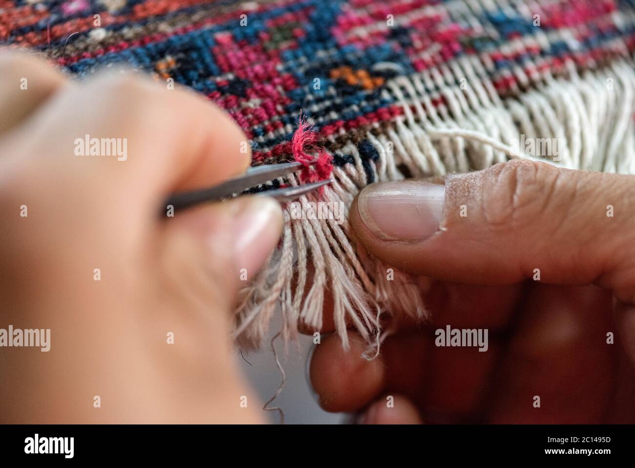 traditional hand sewing fixing old vintage antique persian carpet up close Stock Photo