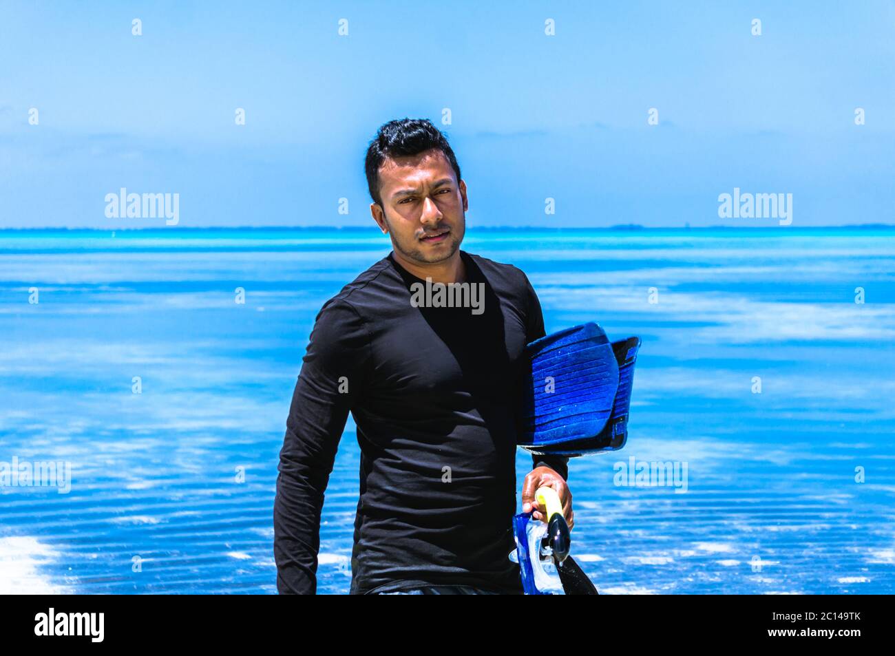 Young Indian man with snorkeling equipment walking out of water in the Maldives Stock Photo