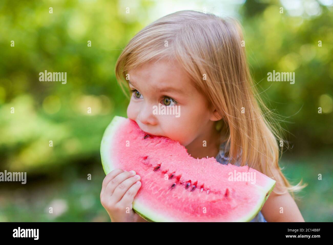 Child eating watermelon in the garden. Kids eat fruit outdoors. Healthy
